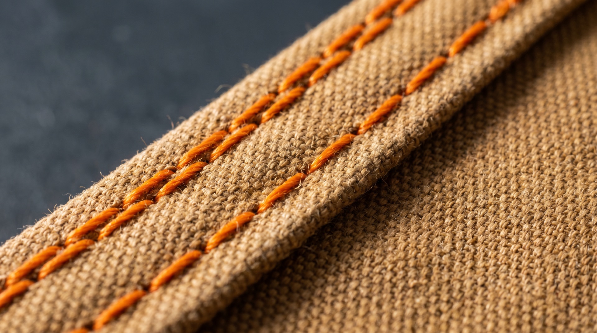 Macro of a double-needle safety-orange stitch line on duck canvas